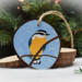 A hand-painted red-breasted nuthatch with sky blue background on a wood slice ornament at Cove Creek Photography.